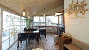 Ein Essbereich mit Holztisch und -stühlen, großen Fenstern und einer Wanddekoration mit einem Baumdesign.