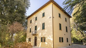 Edifici de dues plantes amb façana simètrica, nombroses finestres amb persianes i una entrada central amb porta.