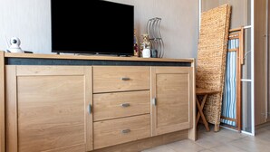 Une chambre moderne avec un meuble en bois, un téléviseur à écran plat et un tapis tissé.