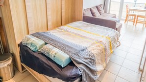 Une chambre à coucher comprenant un lit, une armoire en bois, un canapé et une table à manger avec des chaises.