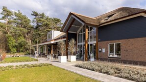A modern building with a large glass entrance, a covered outdoor area, and a brick facade. - Bungalow in Veluwe near Harderwijk (Putten)