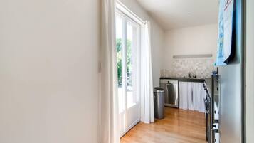 Een moderne keuken met een houten vloer, roestvrijstalen apparatuur en uitzicht op groen.