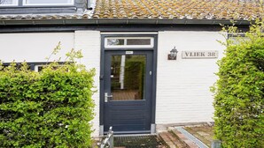 A white building with a dark blue door labeled "WONING 38" and a small sign above the door. - Spacious Group Getaway with Garden (Ulestraten)