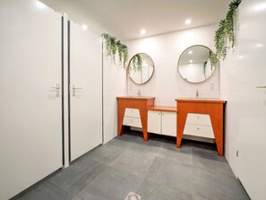 Ein modernes Badezimmer mit zwei Waschbecken, einem Holz-Waschtisch, weißen Schränken und Spiegeln.