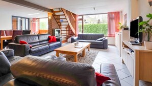 A modern living room with leather sofas, a wooden coffee table, a TV, and a staircase. - Spacious Group Getaway with Garden (Ulestraten)