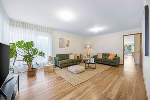 Een woonkamer met twee banken, een salontafel, een televisie en een grote plant.