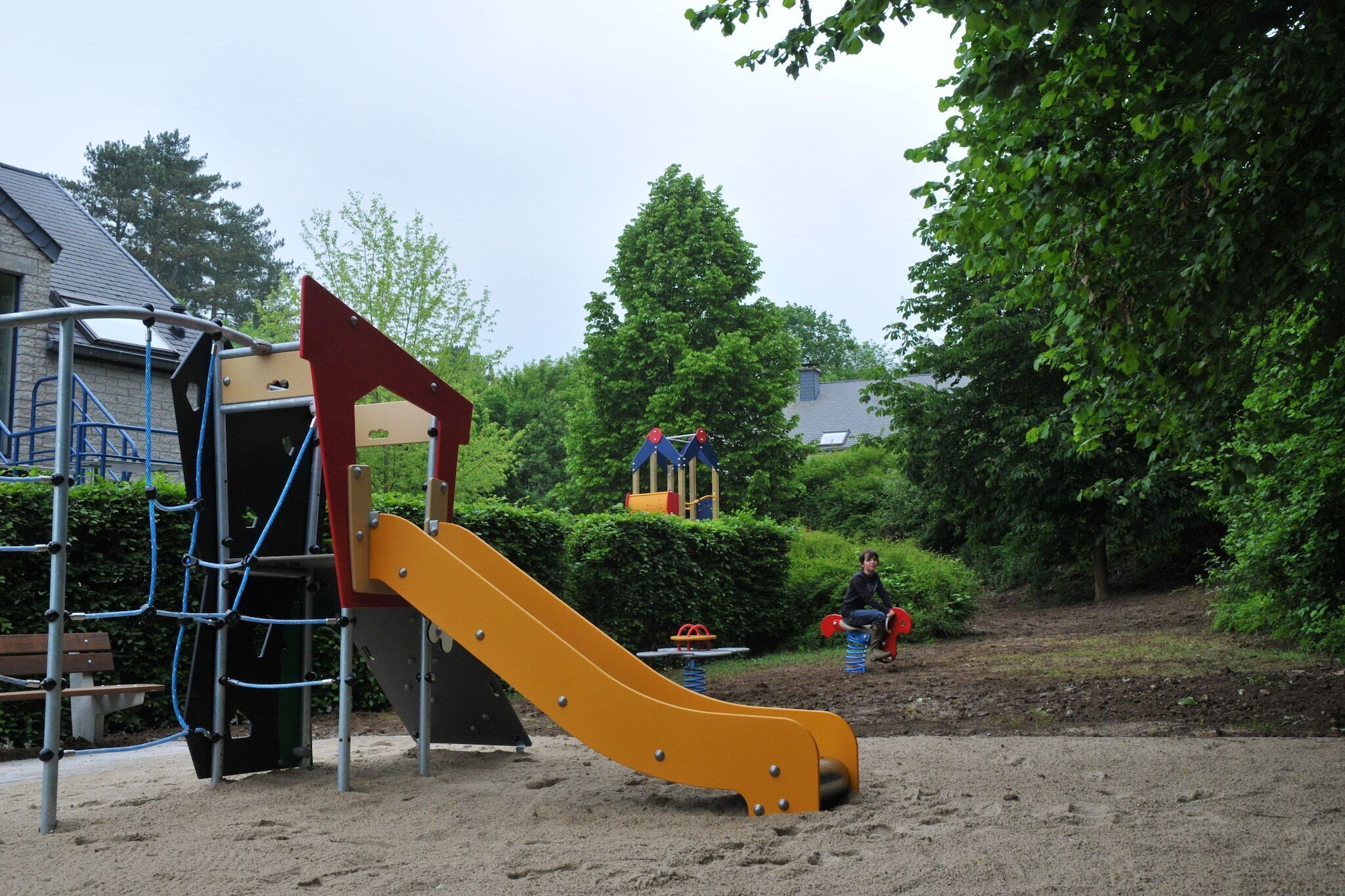 Une aire de jeux avec un toboggan jaune et des structures d’escalade.