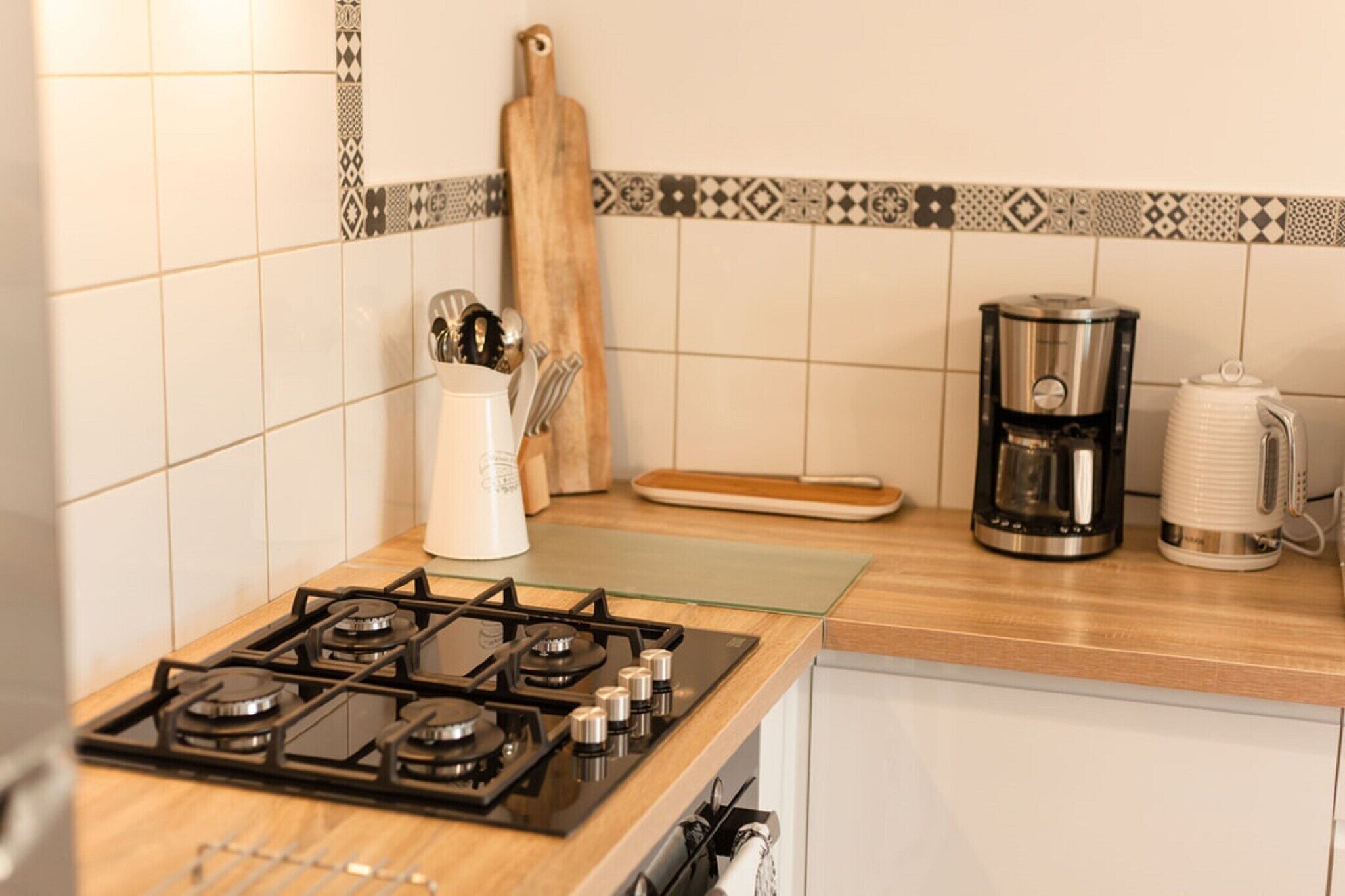 A kitchen with a gas stove, a coffee maker, and a knife block.