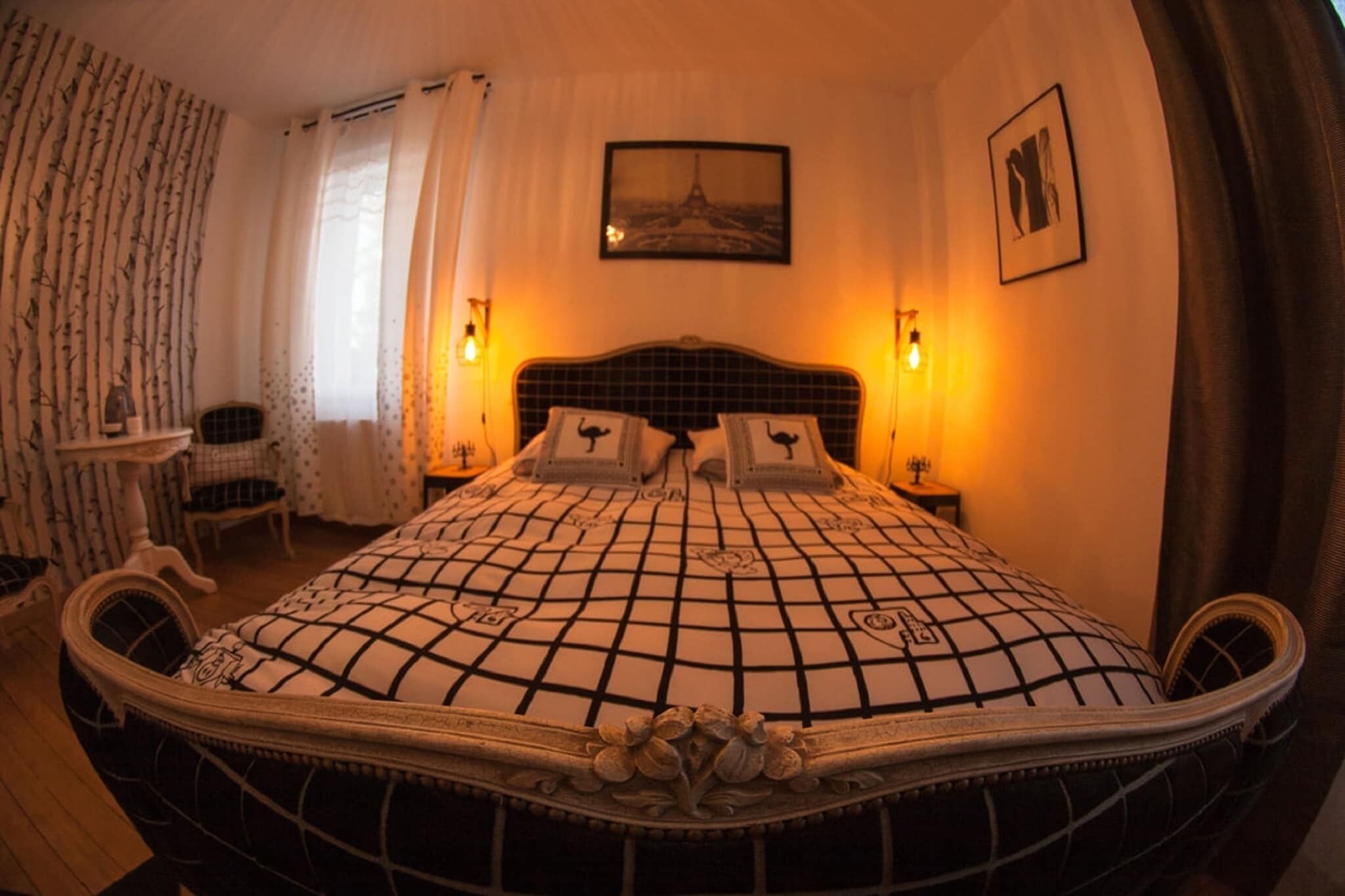 A bedroom with a large bed, two bedside lamps, a chair, and a small table.