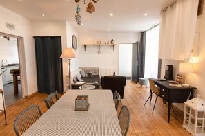 Een gezellige zithoek met een eettafel, een bank, een salontafel en een open haard. In de achtergrond is een keuken zichtbaar.