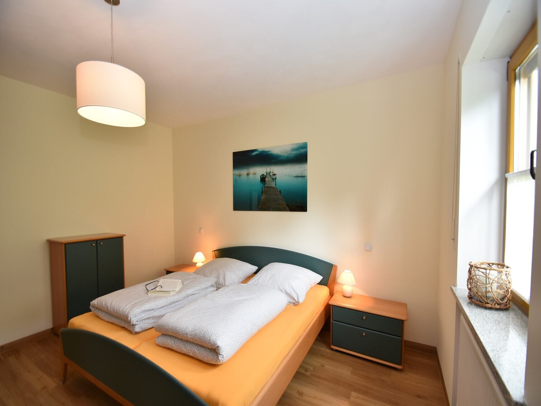 A bedroom with a bed, bedside tables, a lamp, a picture on the wall, and a window.