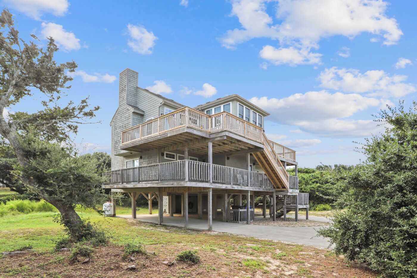 A two-story wooden house with a balcony and a staircase leading to the upper floor.