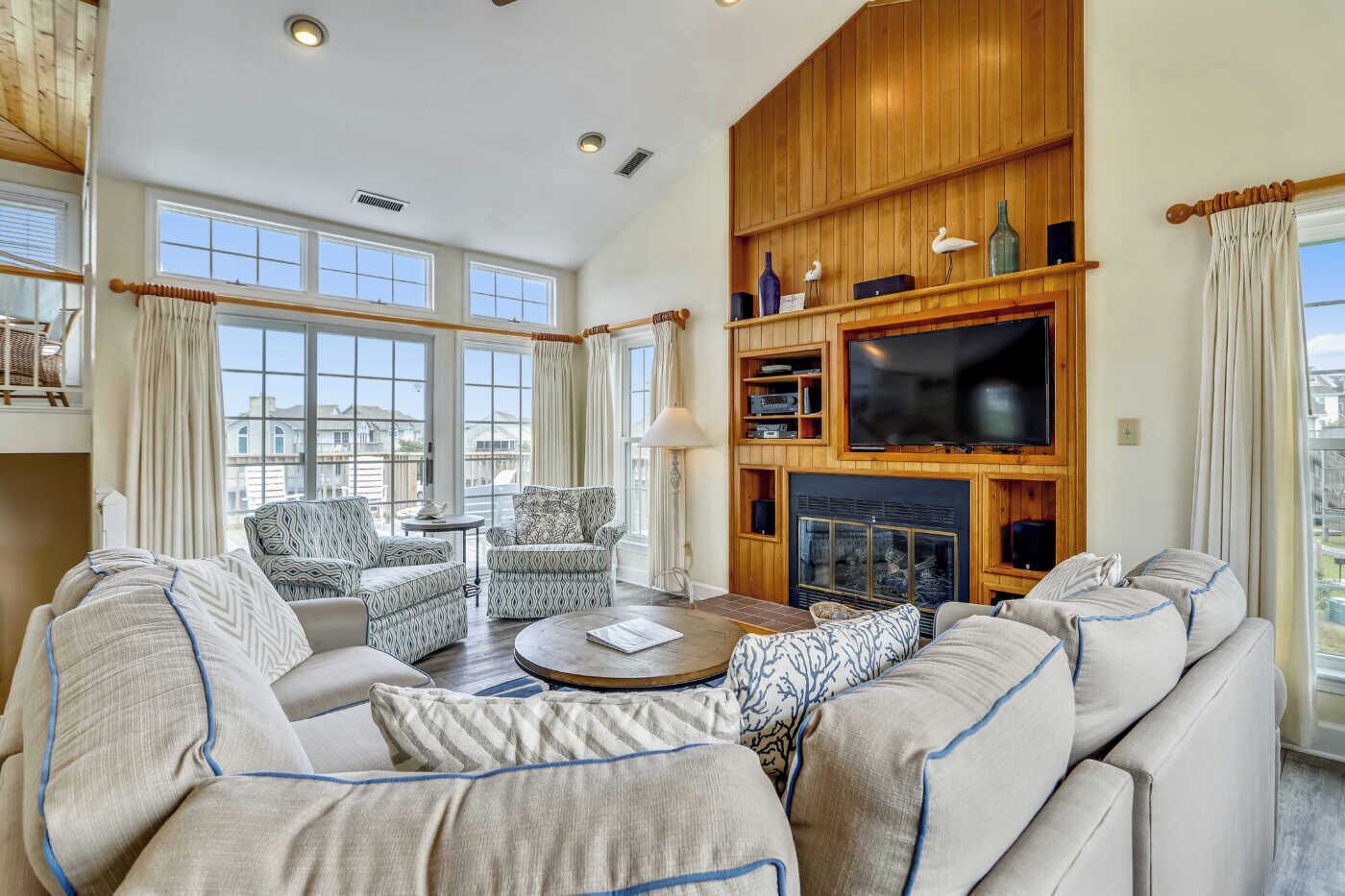 A spacious living room with a fireplace, comfortable seating, and large windows offering a view of the city.