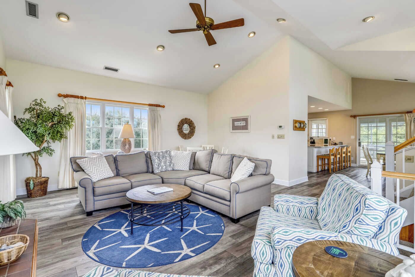 A spacious living room with a sectional sofa, a round coffee table, and a patterned rug.