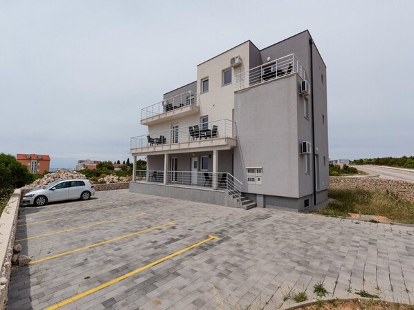 Un edificio moderno de dos pisos con balcón y zona de estacionamiento.