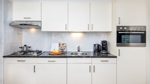 A modern kitchen with white cabinets, a stainless steel oven, a gas stove, and a coffee maker. - Restyled house with fireplace, surrounded by green (Hoogersmilde)