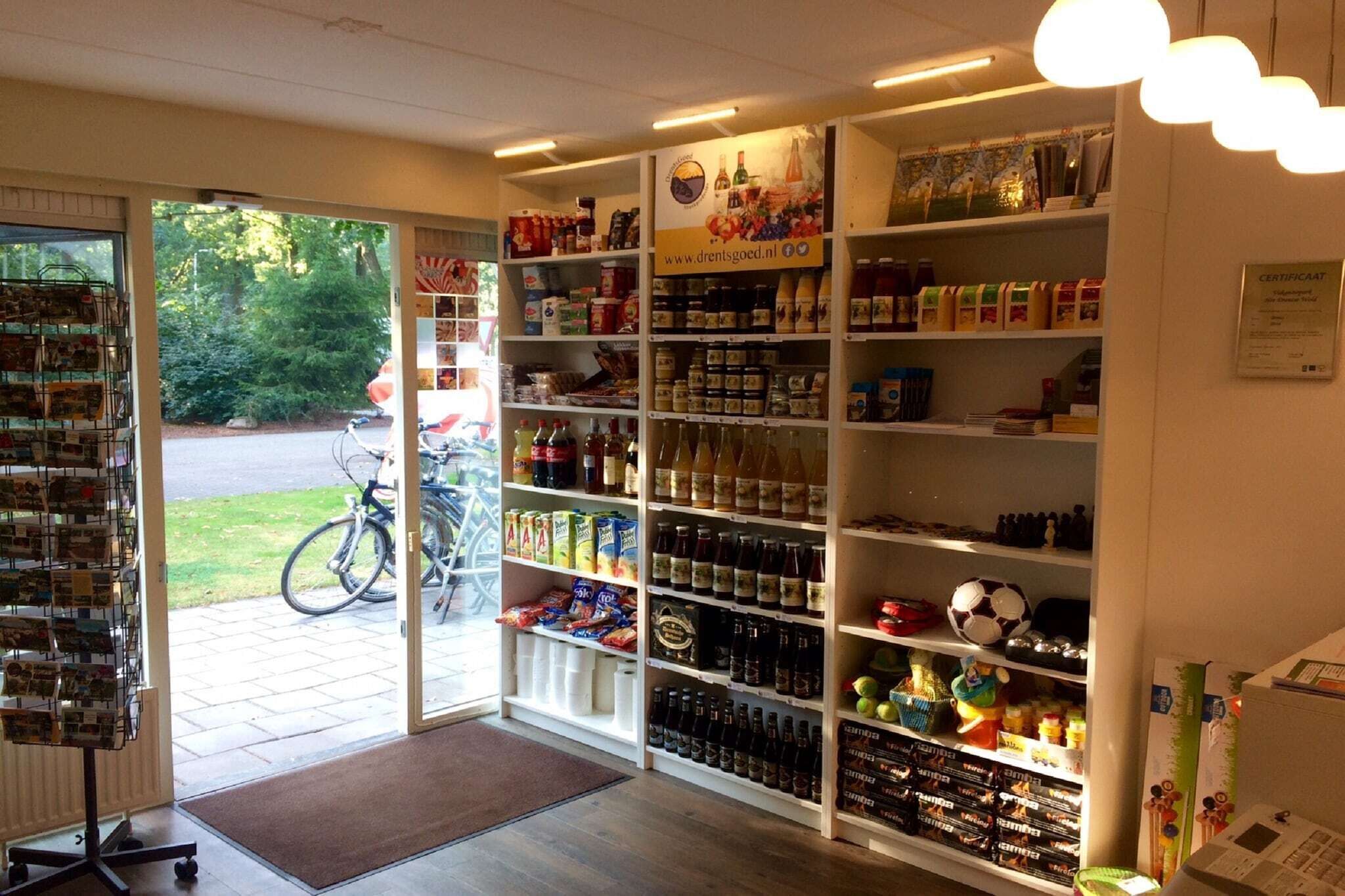A store with shelves stocked with various products, a bicycle outside, and a sign with a website address.