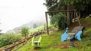 A playground with a wooden slide, swings, and a blue climbing structure. - Apartment in Hainzenberg near Ski Lift (Hainzenberg)