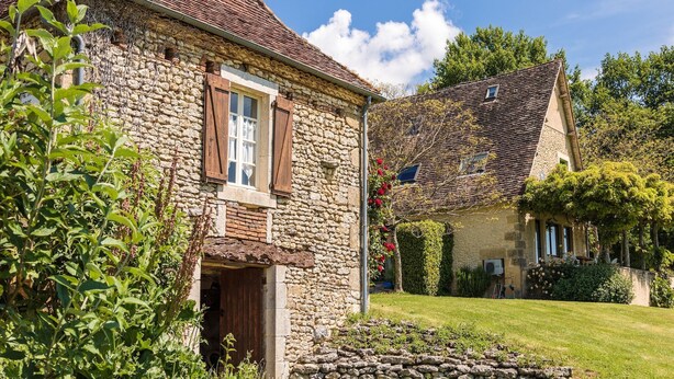 Un bâtiment en pierre doté d’un toit à deux versants, d’une porte en bois et d’une fenêtre avec des volets.