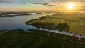 Une vue aérienne d’un paysage rural, avec des champs, une étendue d’eau et une petite île couverte d’arbres.