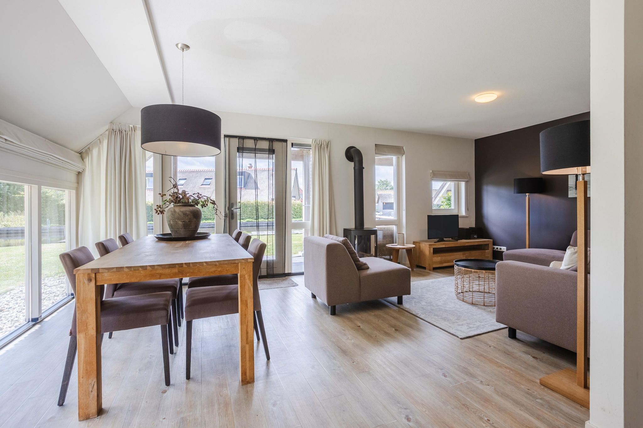 Una sala de estar moderna con comedor, chimenea y televisor.