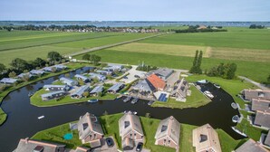 Un quartier résidentiel situé au bord d’un canal, avec des maisons, des bateaux et un petit quai.