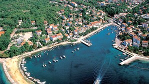 An aerial view of a coastal town with a marina, numerous boats, and residential buildings.