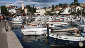 A marina with multiple boats docked, surrounded by buildings and a clear sky.