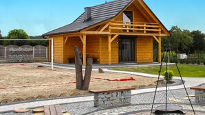 A wooden cabin with a sloped roof, a porch, and a stone bench in front.