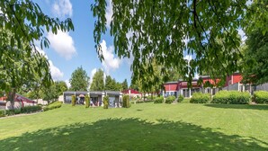 Ein Innenhof mit Rasen, mehreren Gebäuden mit roten Dächern und Bäumen, die Schatten spenden.