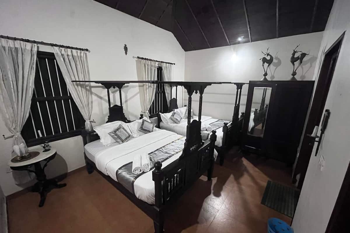 Ein Himmelbett mit weißen Leinen, ein runder Tisch mit Tablett und ein Spiegel an der Wand.