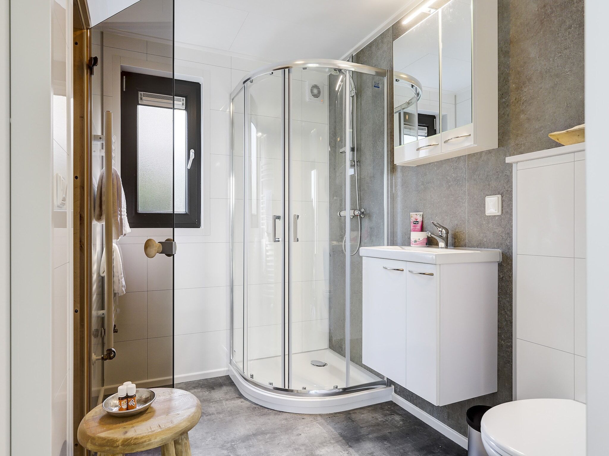 A modern bathroom with a glass shower enclosure, a white sink, and a toilet.