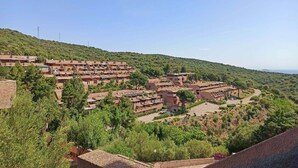 Un village perché sur une colline, avec des maisons à étages et un espace central ouvert, sous un ciel dégagé.