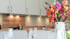 Una mesa de comedor puesta con cristalería transparente y un jarrón con flores de colores.