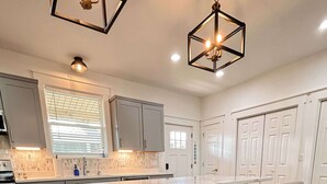 A modern kitchen with a central island, white cabinetry, and a stainless steel range hood. - Bay Views, Short beach walk, 3/2, Community Pool (Port St. Joe)
