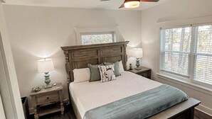 A bedroom with a wooden bed, two bedside tables with lamps, a ceiling fan, and a window with blinds. - Bay Views, Short beach walk, 3/2, Community Pool (Port St. Joe)