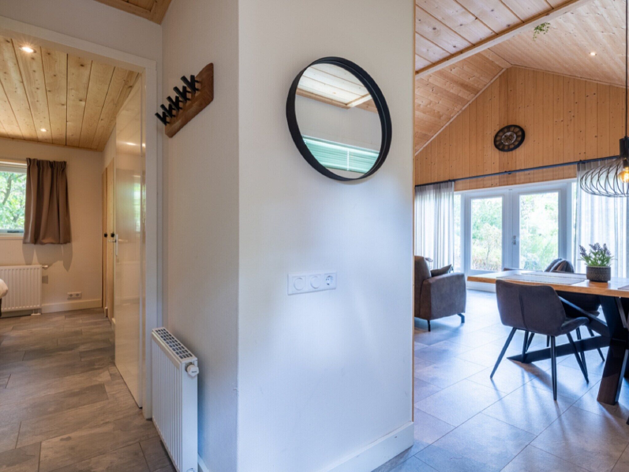 Un interno moderno con soffitto in legno, un'area pranzo con tavolo e sedie e un grande specchio a parete.