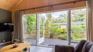 Una sala de estar moderna con techo de madera, un sofá de cuero marrón, una mesa de centro de madera y un televisor a la izquierda.