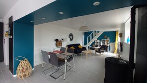 Een moderne woonkamer met een eethoek, een trap en een boekenkast.