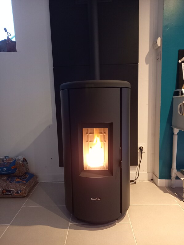 A FreePoint wood-burning stove with a visible fire, located in a room with tiled flooring and a window.