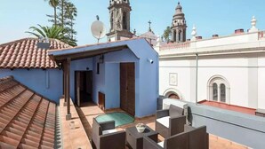 Eine Dachterrasse mit Gartenmöbeln, einem Pool und Blick auf historische Gebäude mit Kuppeln und Kreuzen.