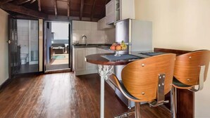 Eine kleine Küche mit Holzschränken, einem Edelstahlkühlschrank und einem Essbereich mit zwei Holzstühlen.