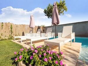 A poolside area with white wicker lounge chairs, a bench, and two umbrellas. - Holiday Home Fraga with Private Pool (Fraga)