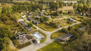 Luchtbeeld van een woongebied met moderne huizen, een centraal gelegen zwembad en verzorgde tuinen.
