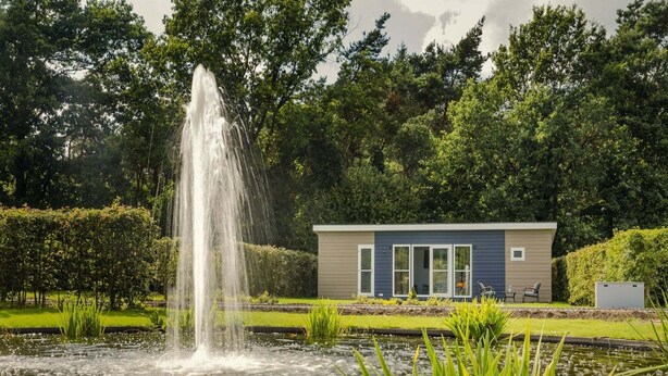 Een modern gebouw met een waterfontein in een tuin.