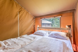 A tented room with a bed, a window, and a lamp.