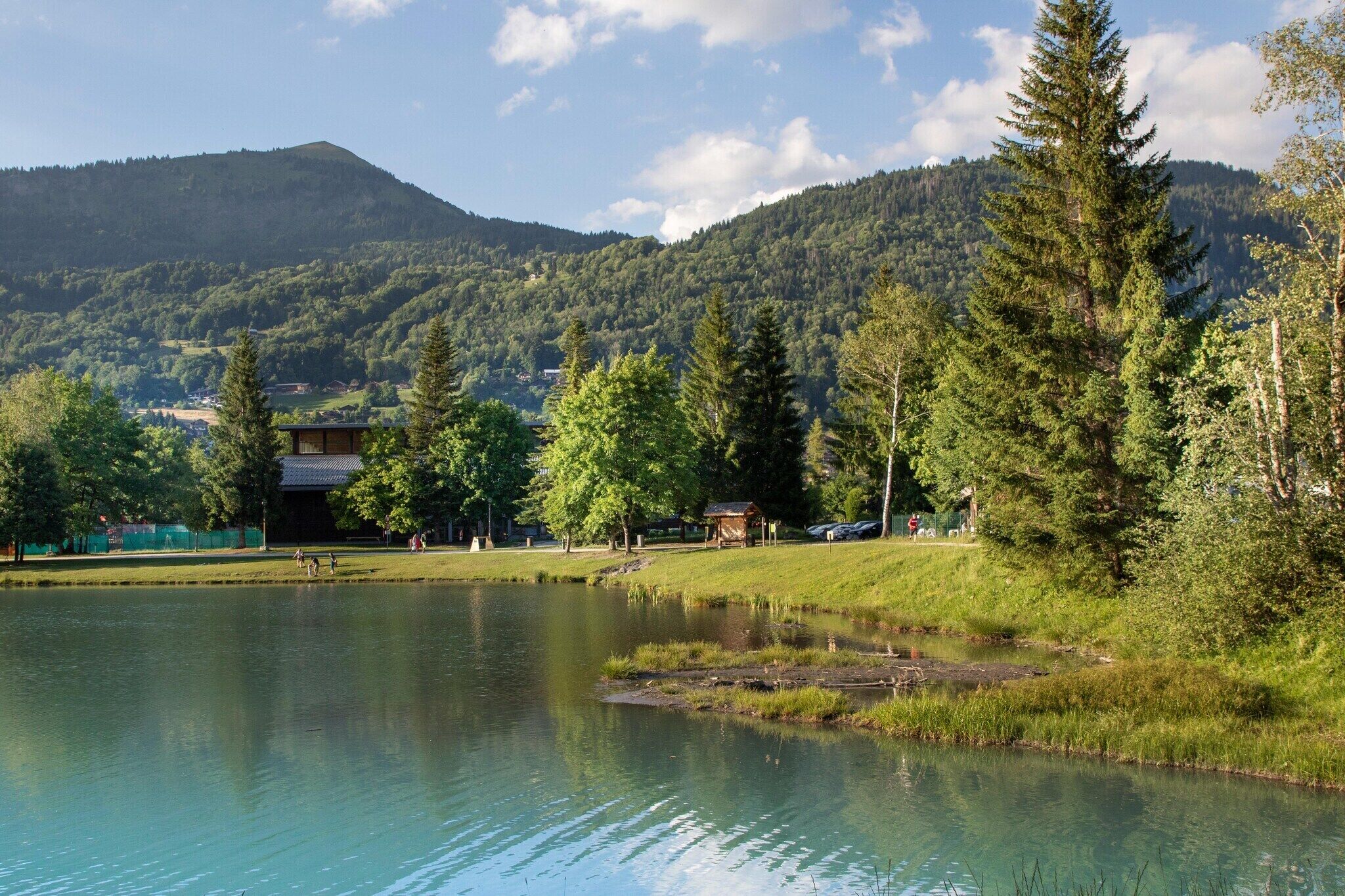 Une vue sur le lac, avec une montagne en arrière-plan, un belvédère et un bâtiment doté d’un toit en pente.