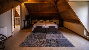 A bedroom with a sloped ceiling, a bed with two pillows, a bedside table, a rug, and a radiator. - Stay at Oranjezon Dunes (Vrouwenpolder)