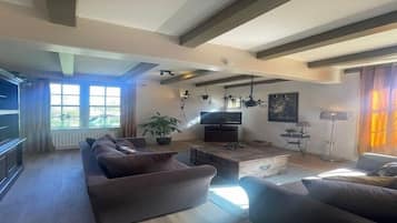 Amplia sala de estar con un sofá grande, un televisor de pantalla plana y una mesa de centro.