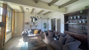 A living room with a sofa, coffee table, and a wooden cabinet with decorative items. - Stay at Oranjezon Dunes (Vrouwenpolder)